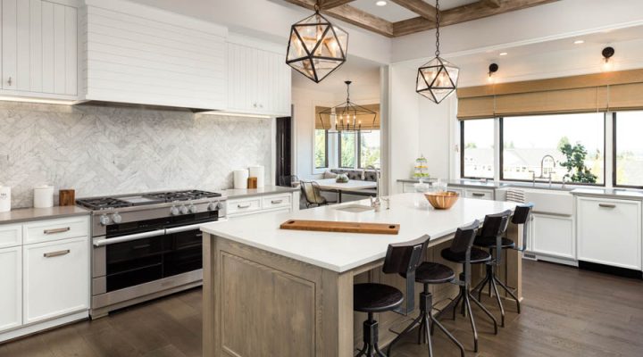 Luxurious kitchen interior featuring white shaker cabinets, herringbone backsplash, wooden beams, and modern appliances with pendant lighting over an island.