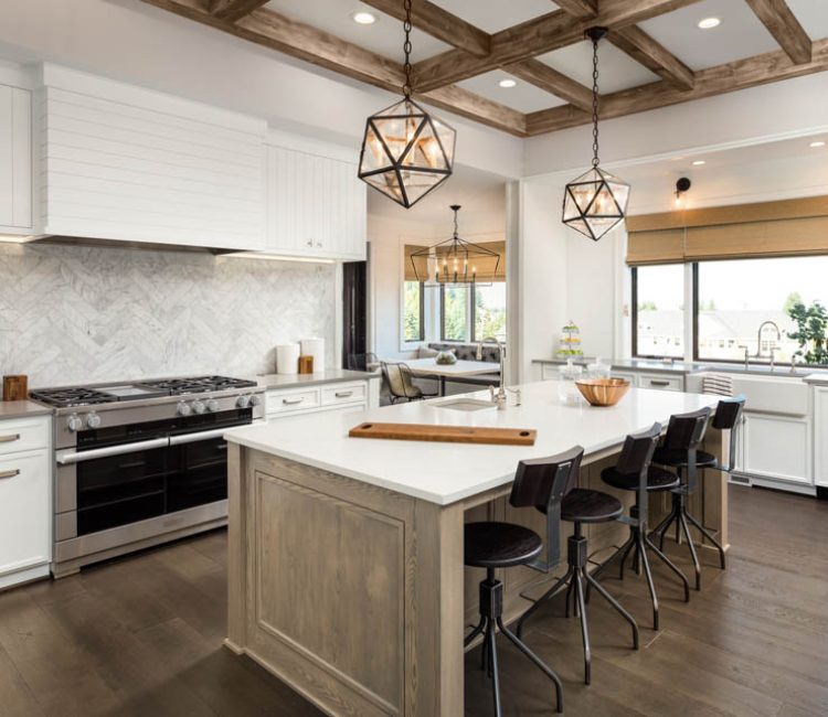 Luxurious kitchen interior featuring white shaker cabinets, herringbone backsplash, wooden beams, and modern appliances with pendant lighting over an island.