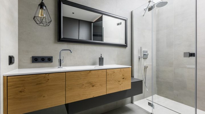 Modern minimalist bathroom with sleek design features, including a wooden vanity against a concrete-textured wall, frameless mirror, and a spacious walk-in shower.